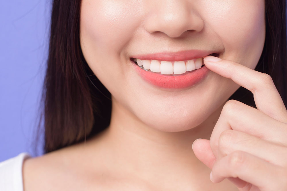 A girl pointing the white teeth with her finger