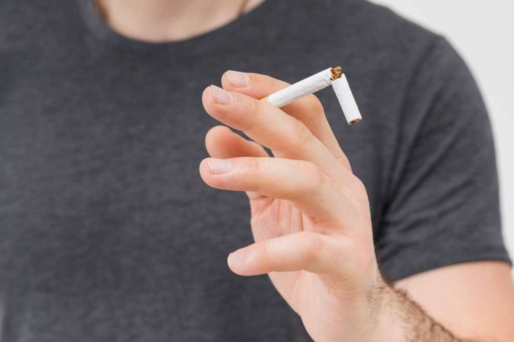 Close-up of man breaking cigarette showing smoking effects on dental implants