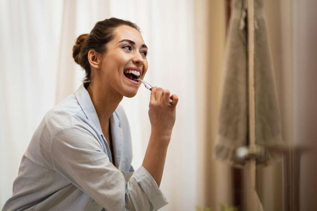 Woman brushing teeth to reduce wisdom teeth bad breath naturally