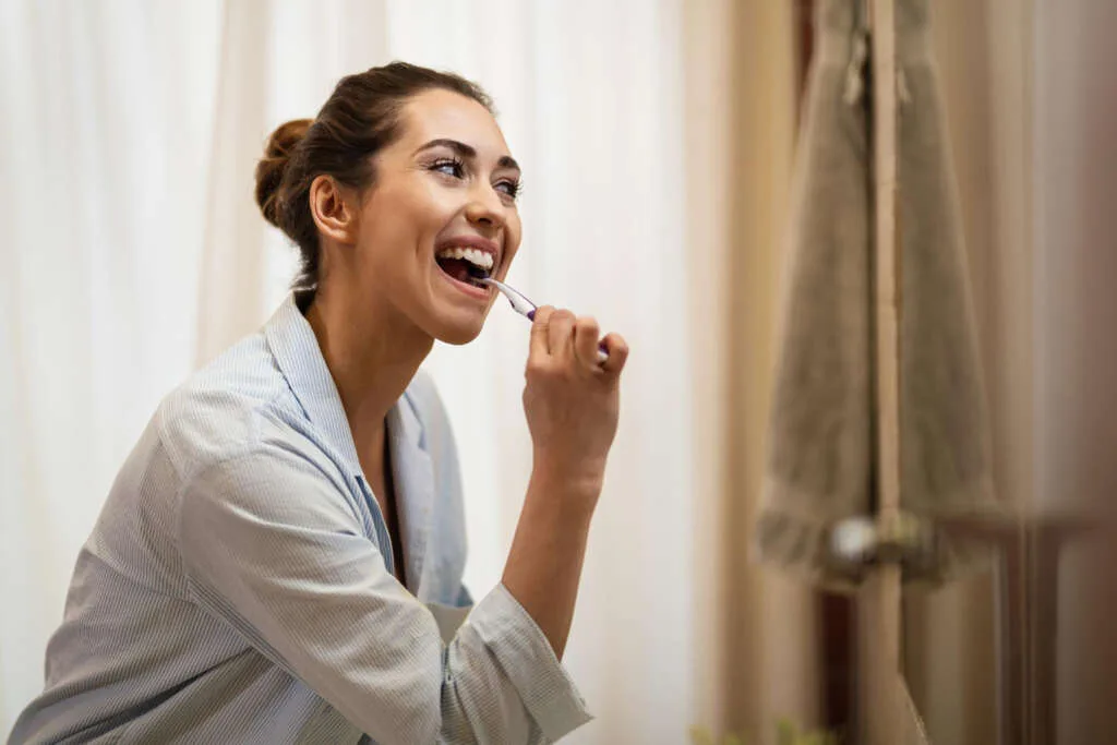Woman brushing teeth to reduce wisdom teeth bad breath naturally